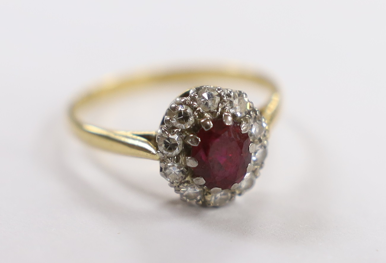 An 18ct, ruby and diamond set oval cluster ring, size N/O, gross weight 2.5 grams.